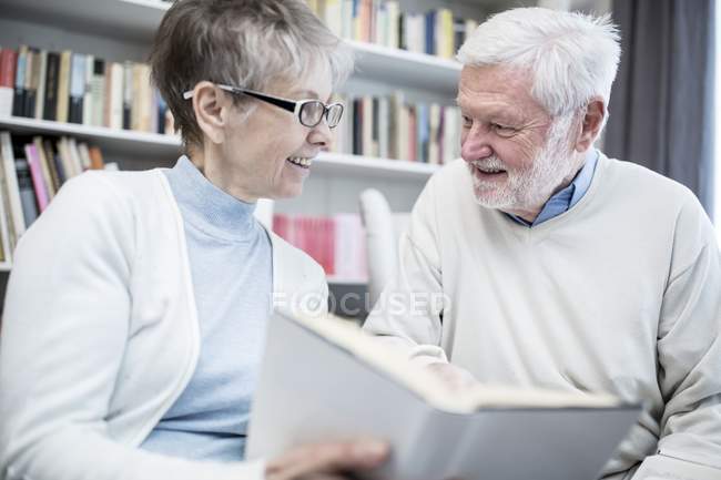 Senior couple reading book in armchair together. — Stock Photo