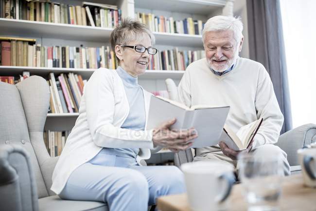 Fröhliches Seniorenpaar liest gemeinsam Bücher. — Stockfoto