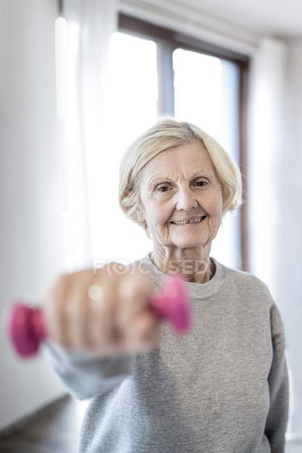 Senior woman holding pink hand weight. — Stock Photo