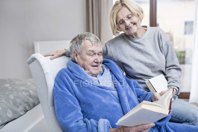 Casal sênior ler livros em poltrona em casa de cuidados . — Fotografia de Stock