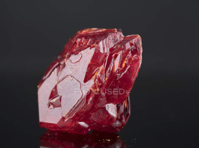 Red mineral gemstone on mirror surface. — Stock Photo