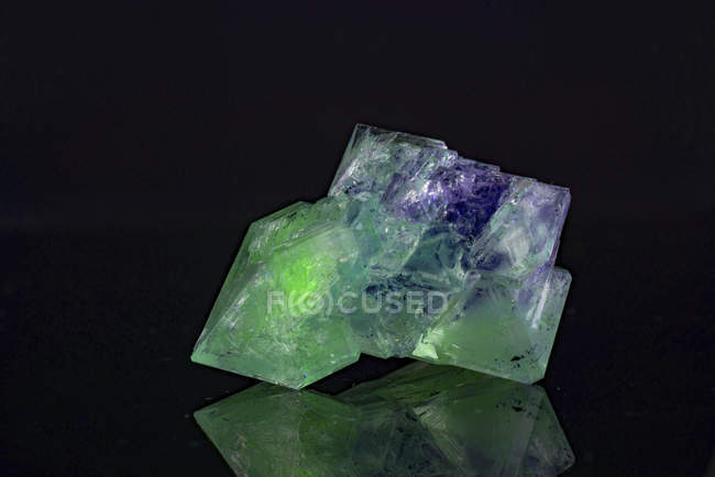 Green mineral gemstone on mirror surface. — Stock Photo