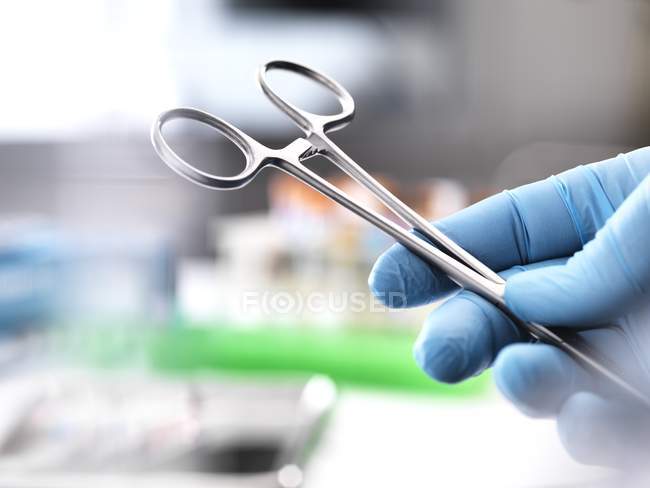 Close-up of surgical scissors in surgeon hand at operating theater. — Stock Photo