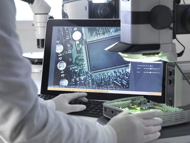 Cropped view of engineer using stereo microscope for inspecting printed circuit board. — Stock Photo