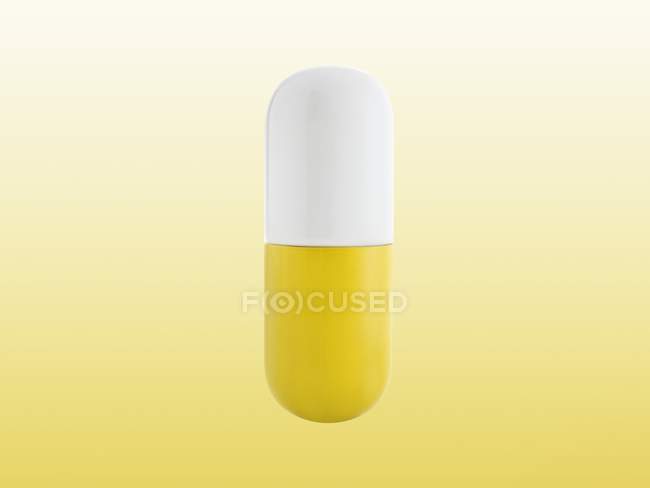 Yellow and white capsule, studio shot. — Stock Photo