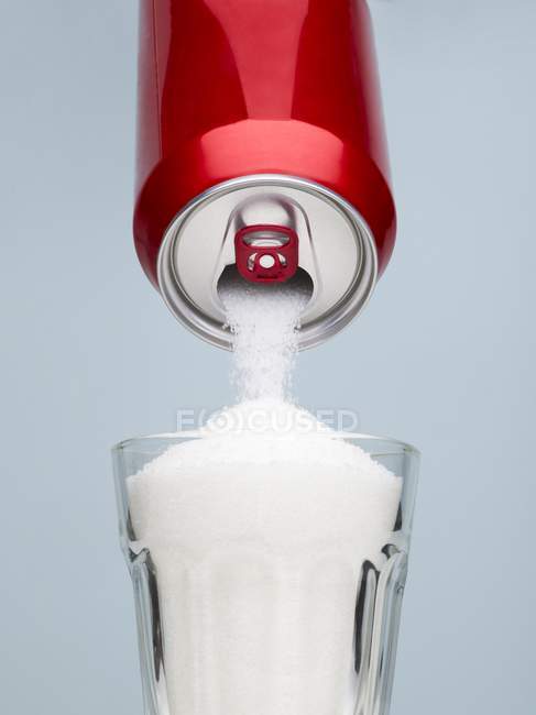 Сахар выливается из банки с напитками в стакан . — стоковое фото