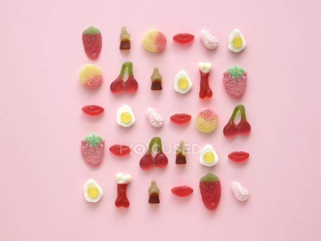 Arrangement de bonbons gommeux colorés en forme sur fond rose
. — Photo de stock