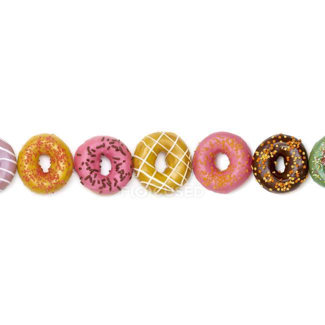 Donuts coloridos em uma fileira, tiro estúdio . — Fotografia de Stock