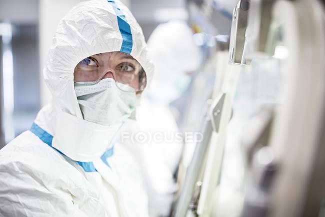 Técnico de laboratório em terno de proteção, máscara facial e óculos de segurança em laboratório estéril . — Fotografia de Stock