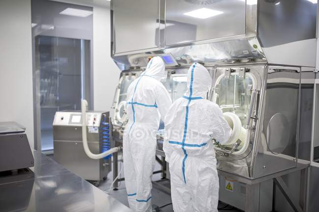 Techniciens travaillant avec la boîte à gants dans un laboratoire biomédical scellé et stérile . — Photo de stock