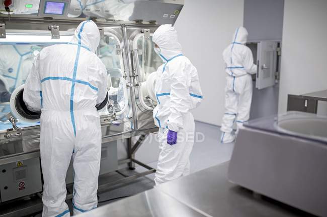 Técnicos que trabalham em laboratório biomédico selado e estéril . — Fotografia de Stock