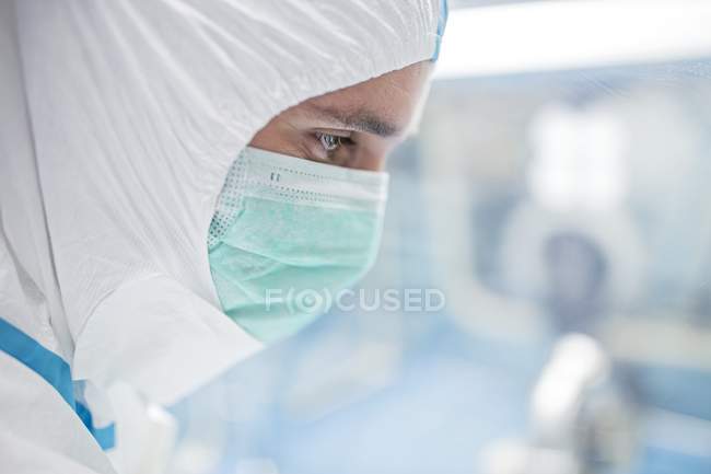 Primo piano del tecnico di laboratorio in tuta protettiva e maschera facciale in laboratorio sterile . — Foto stock