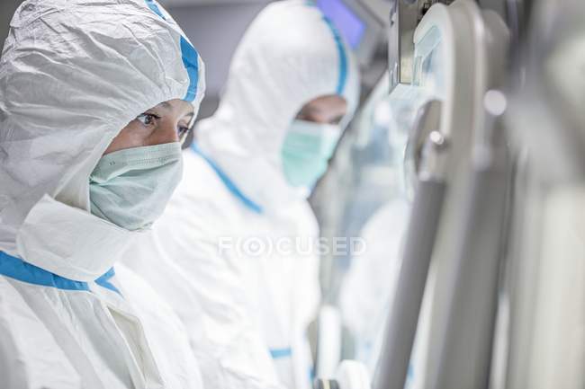 Tecnici che lavorano in laboratorio biomedico sigillato e sterile . — Foto stock