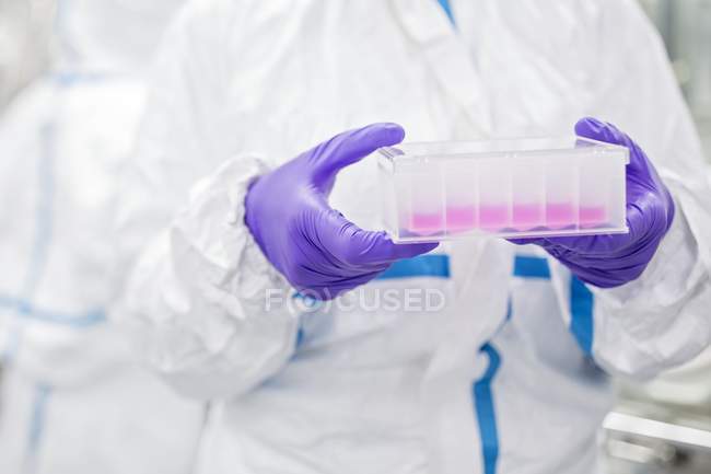 Vista ritagliata del tecnico di laboratorio che trasporta il corredo di prova basato sulle cellule nel laboratorio di bioingegneria . — Foto stock