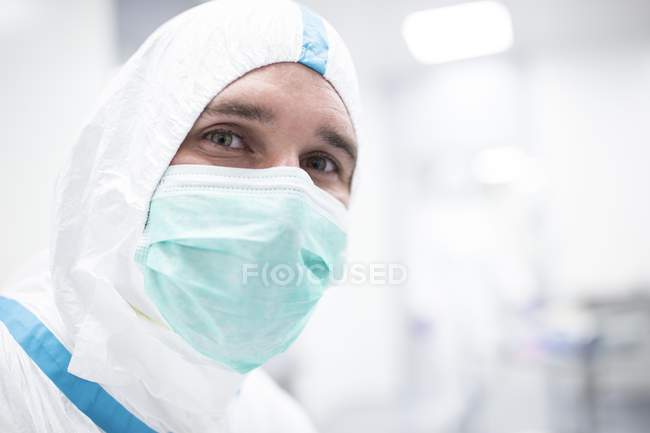 Close-up of male lab technician in protective suit and face mask in sterile laboratory. — Stock Photo