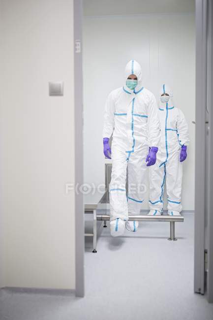 Техніки, що проходять через кабіну знезараження перед входом у стерильну лабораторію . — стокове фото