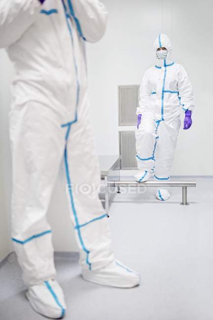 Techniker gehen durch eine Dekontaminationskabine, bevor sie ein steriles Labor betreten. — Stockfoto