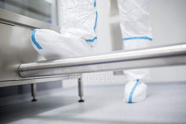 Close-up of technician in protective clothing walking through decontamination cabin. — Stock Photo