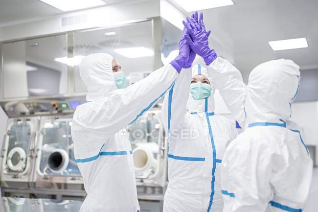 Lab technicians high-fiving in sterile laboratory environment. — Stock Photo