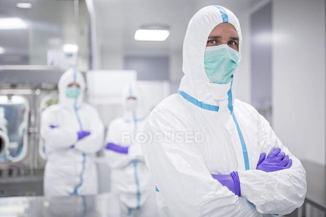 Лаборант в захисному одязі з колегами в стерильному лабораторному середовищі . — стокове фото