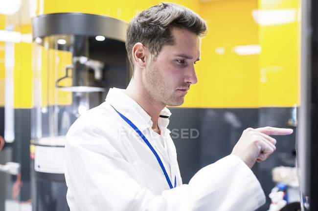 Técnico masculino que programa la máquina de electrospinning en laboratorio de la nanofibra . - foto de stock