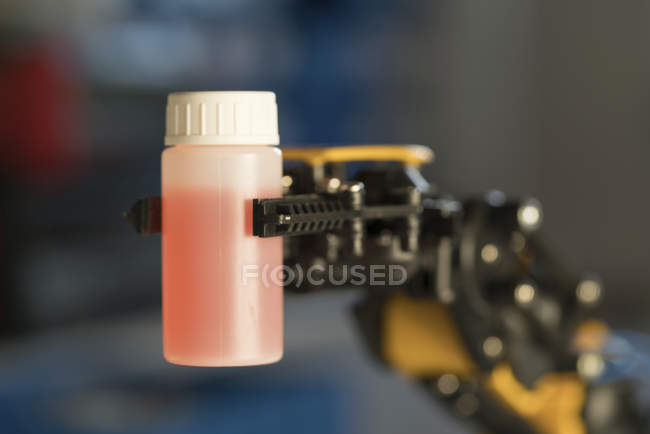 Robotic arm holding bottle with liquid. — Stock Photo