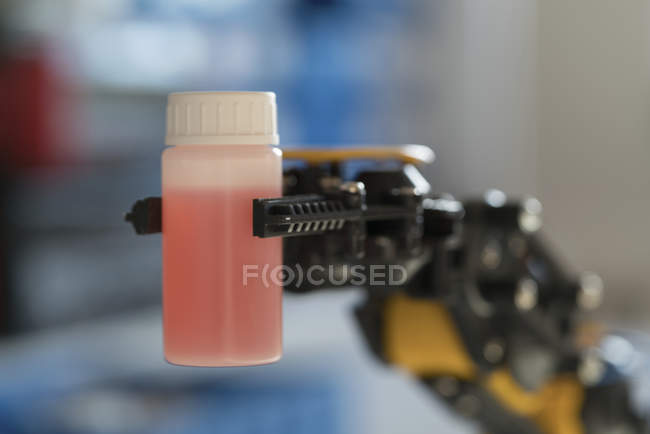 Роботизированная рука держит бутылку с жидкостью . — стоковое фото