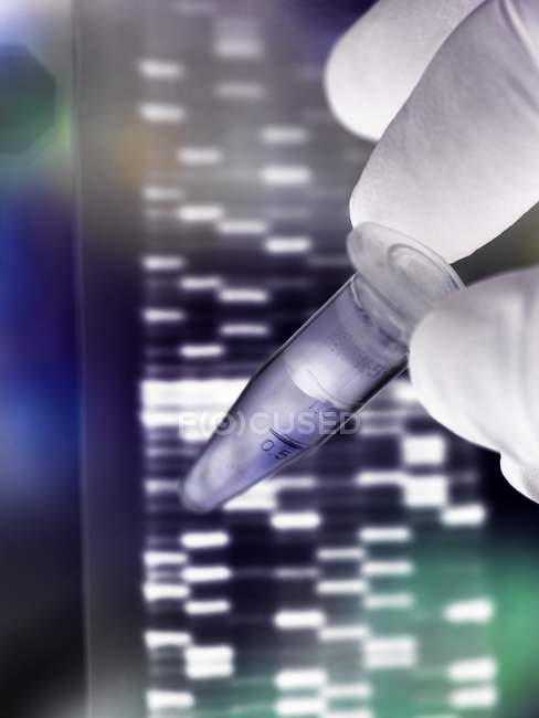 Вчений, тримаючись за зразок ДНК трубки з autoradiograph на ДНК гель. — стокове фото