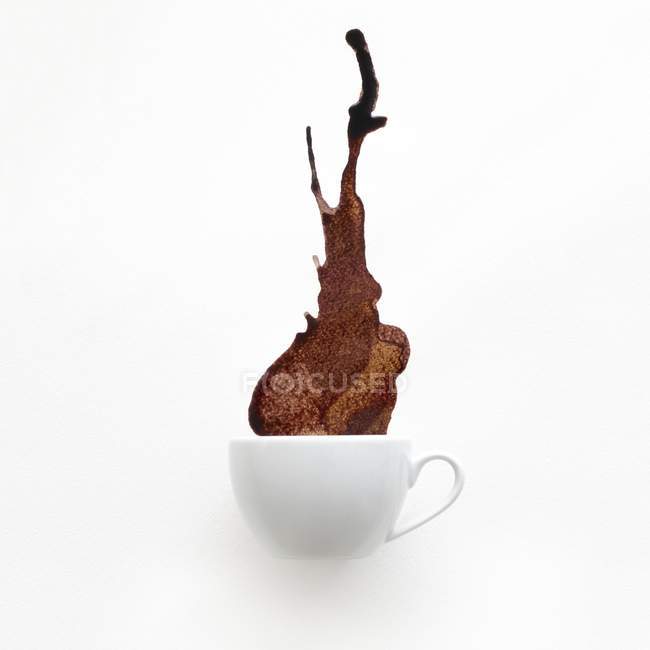 Cup of coffee spilling against white background. — Stock Photo