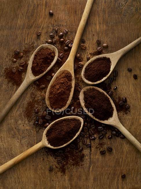 Cucharas de madera con café molido sobre fondo rústico . - foto de stock