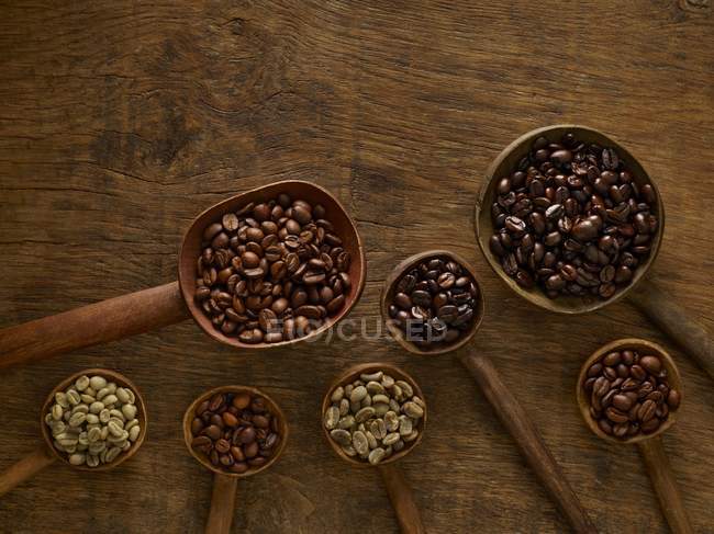 Cucharas de madera con granos de café sobre fondo rústico . - foto de stock