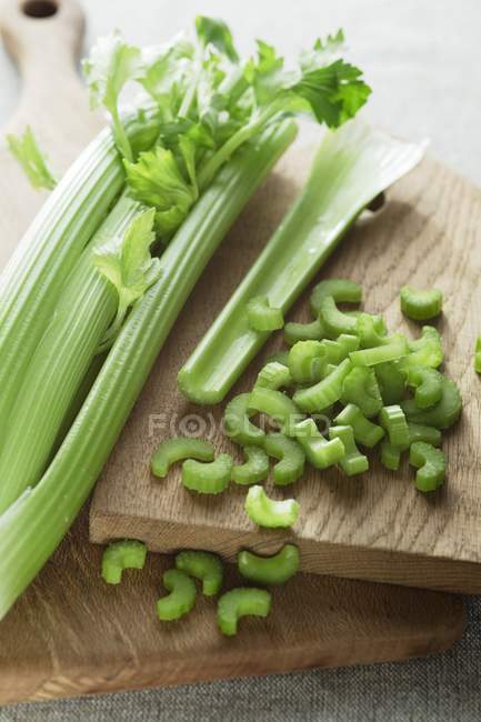 Head of celery on wooden chopping board with cut slices. — Stock Photo