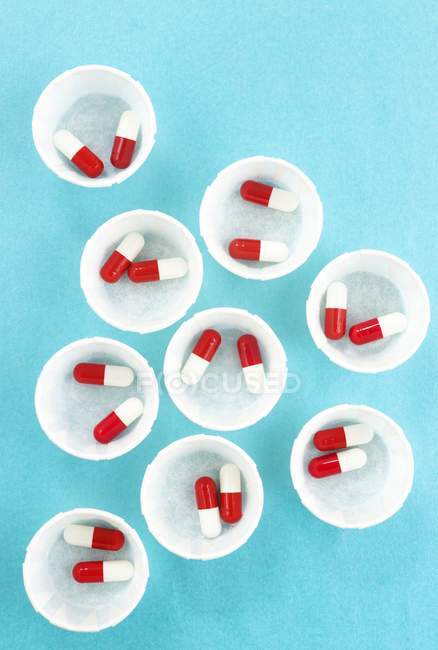 Вид сверху на бумажные аптечки с красными и белыми капсулами для лекарств . — стоковое фото