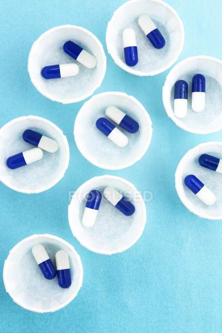 Vista dall'alto di vasi medicinali di carta con capsule blu e bianche
. — Foto stock