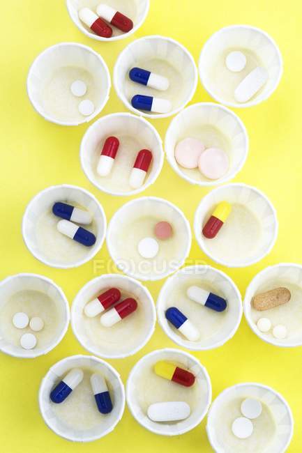 Вид зверху папір медицини горщики з різних таблетки на жовтому фоні. — стокове фото
