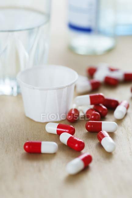 Capsules de drogues rouges et blanches par tasse en papier . — Photo de stock