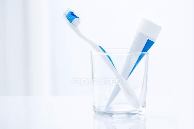 Zahnbürste und Zahnpasta im Glas vor glattem Hintergrund. — Stockfoto