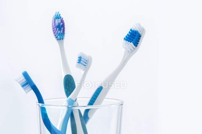 Blaue Zahnbürsten im Glas vor glattem Hintergrund. — Stockfoto