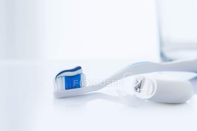 Cepillo de dientes con pasta de dientes y hilo dental sobre fondo blanco . - foto de stock