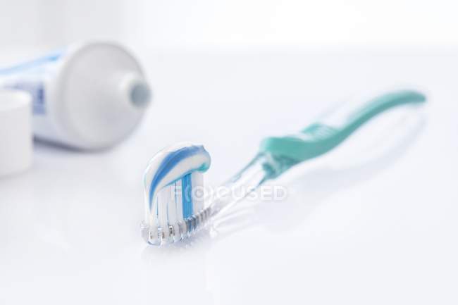 Cepillo de dientes con pasta de dientes blanca y azul sobre fondo blanco . - foto de stock