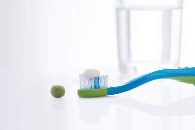 Toothbrush with pea-sized amount of toothpaste against white background. — Stock Photo
