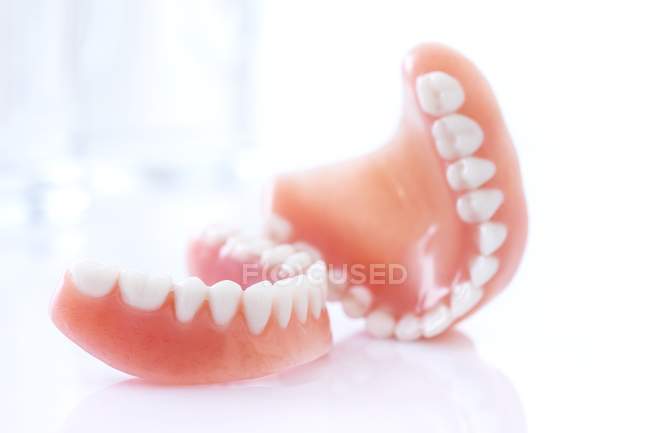Prótesis dentales sobre mesa sobre fondo blanco . - foto de stock
