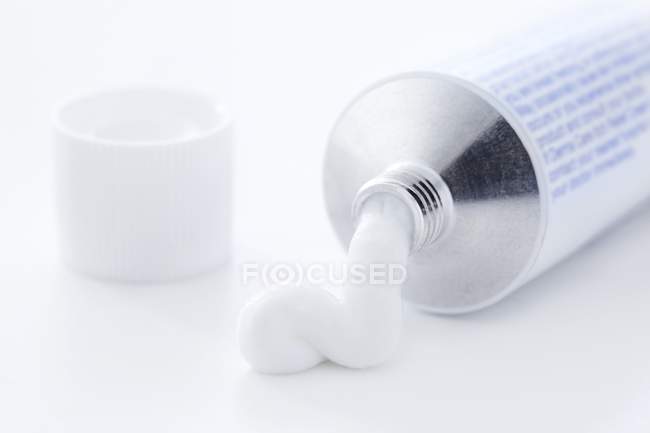 Close-up of white medical cream coming out of tube. — Stock Photo