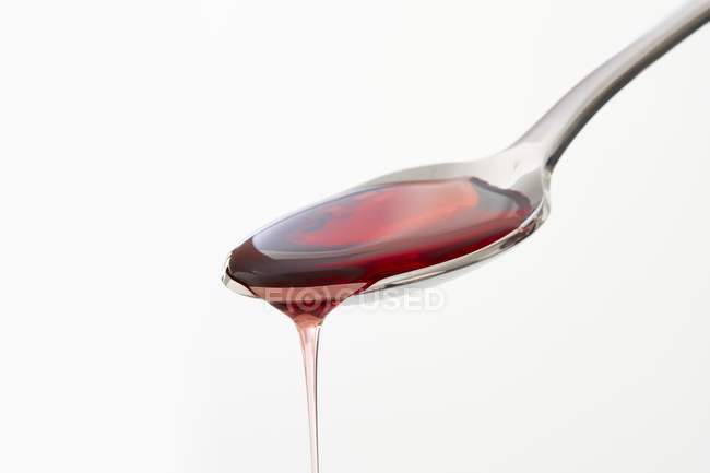 Cough syrup dripping from spoon on white background, studio shot. — Stock Photo