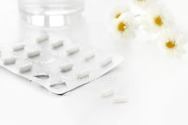 Antihistamine tablets and flowers, studio shot. — Stock Photo