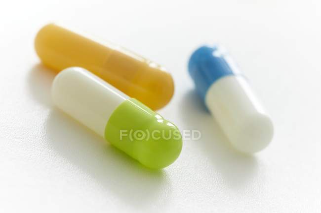 Multicolored capsules on white background, studio shot. — Stock Photo