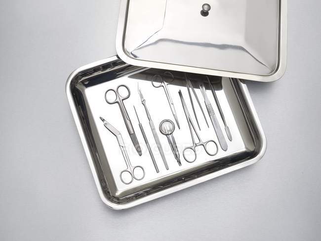 Surgical equipment in tray against grey background. — Stock Photo
