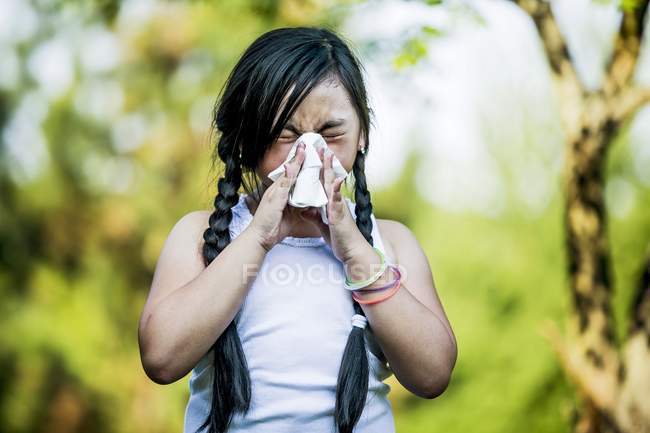 Elemental niña enferma usando pañuelo mientras estornuda al aire libre
. - foto de stock