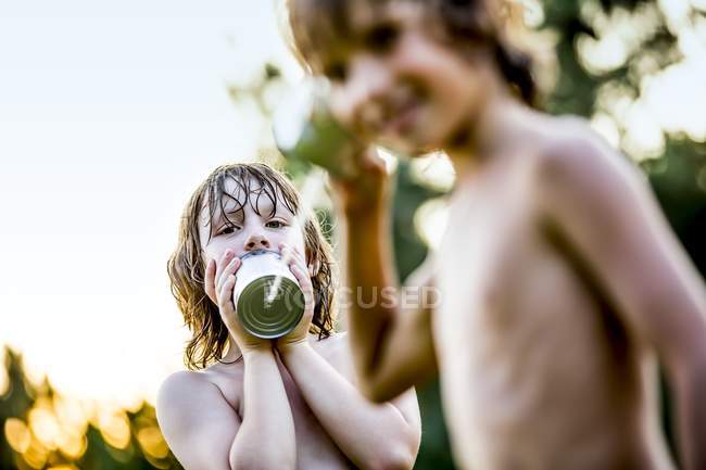 Boys playing with tin can telephone. — Stock Photo