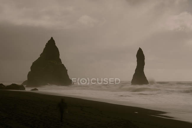 Rock formation on shore by water in twilight, Reynisdrangar, Vik, Iceland. — Stock Photo